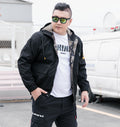 Black hooded utility jacket with camouflage inner facing and front flap pockets, worn by a model
