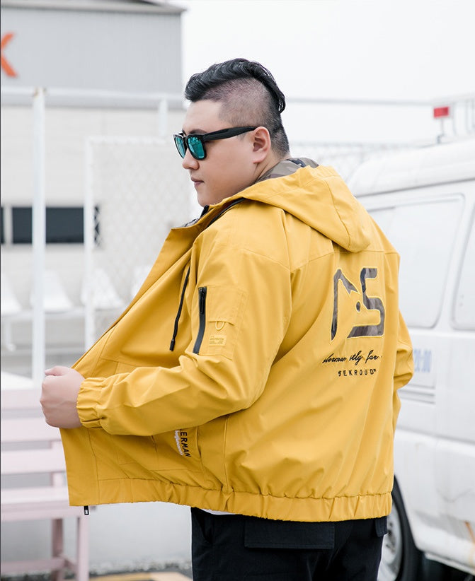 Yellow hooded utility jacket with camouflage back graphic and gathered hem, worn by a model
