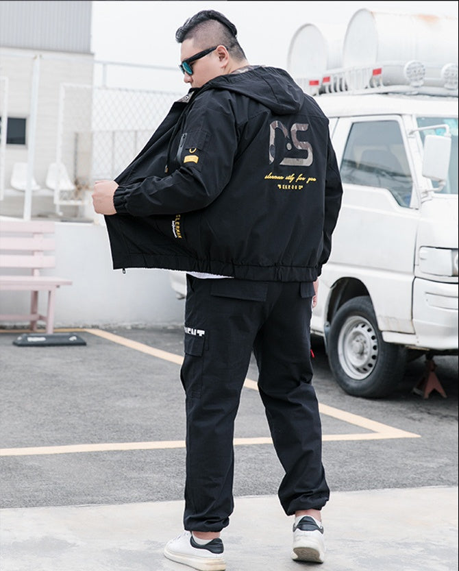 Black hooded utility jacket with camouflage back graphic and yellow lettering, worn by a model

