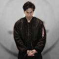 Black oversized flight bomber jacket with a front zip and red sleeve pocket pull tab, worn by a model
