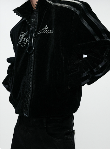 Close-up of a black gothic jacket showing the oversized ring zip and contrast stripes along the shoulder and sleeve
